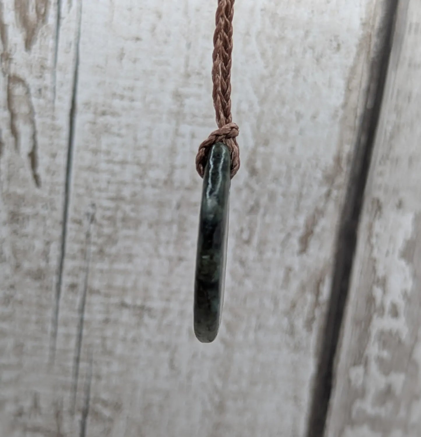 Tumble polished New Zealand Pounamu greenstone pendant.