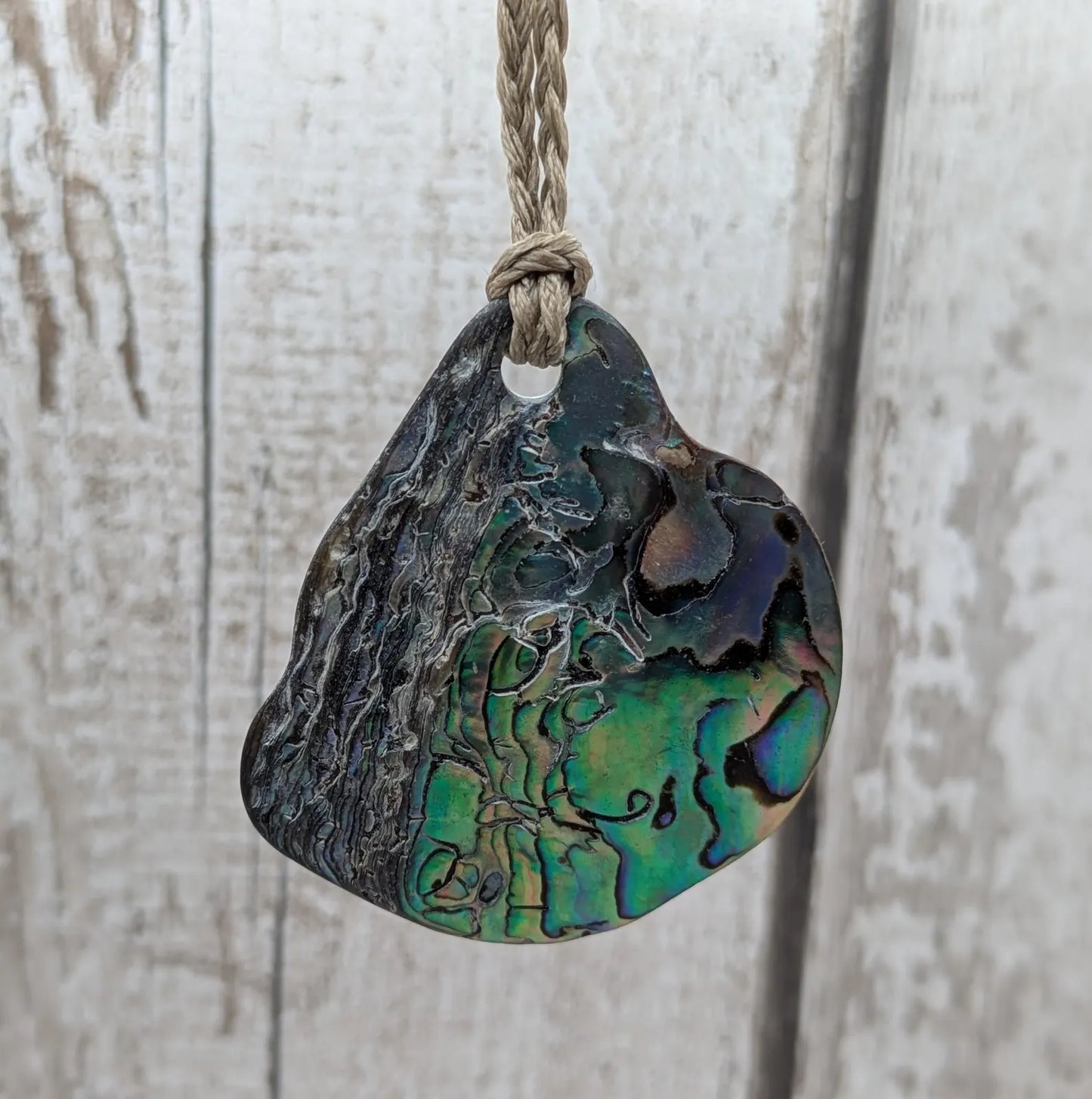 Free form naturally tumbled New Zealand rainbow Pāua pendant.