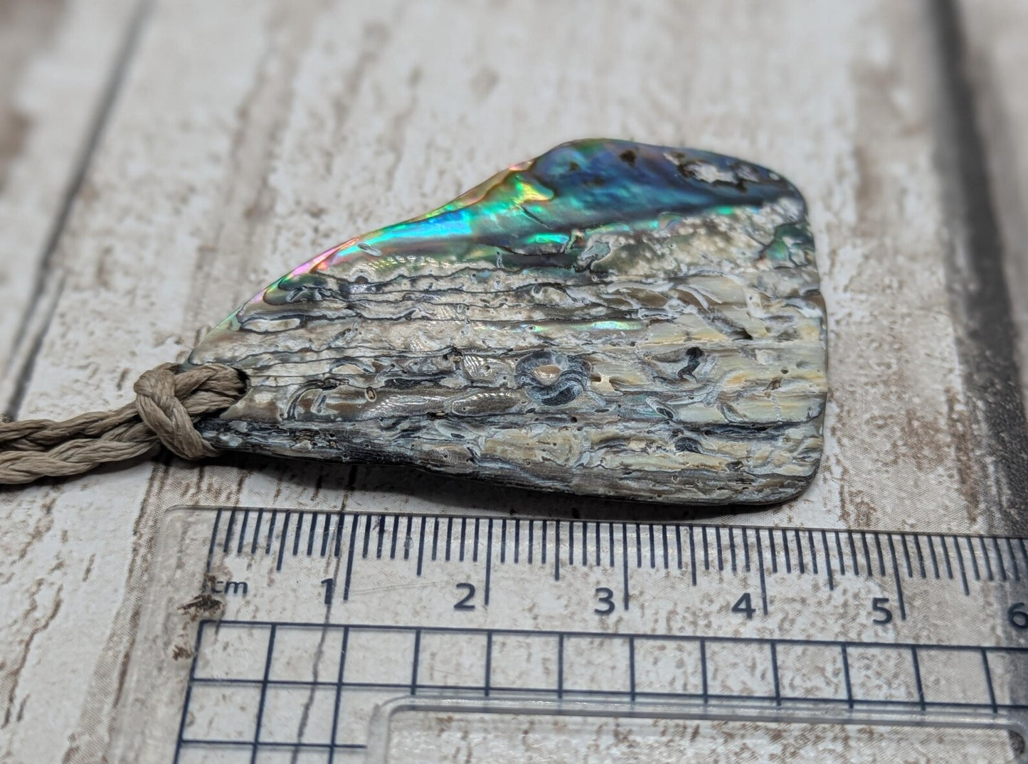 Naturally tumbled New Zealand rainbow Pāua abalone pendant.