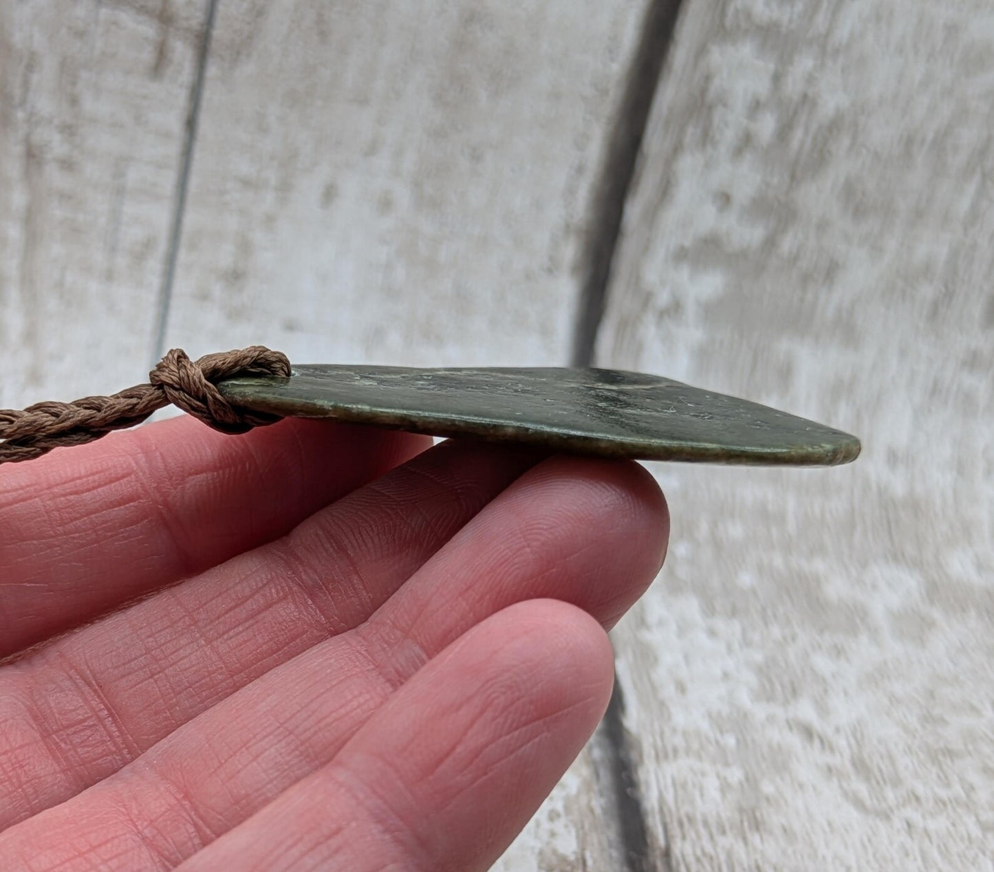 Tumbled polished New Zealand Pounamu greenstone pebble pendant.