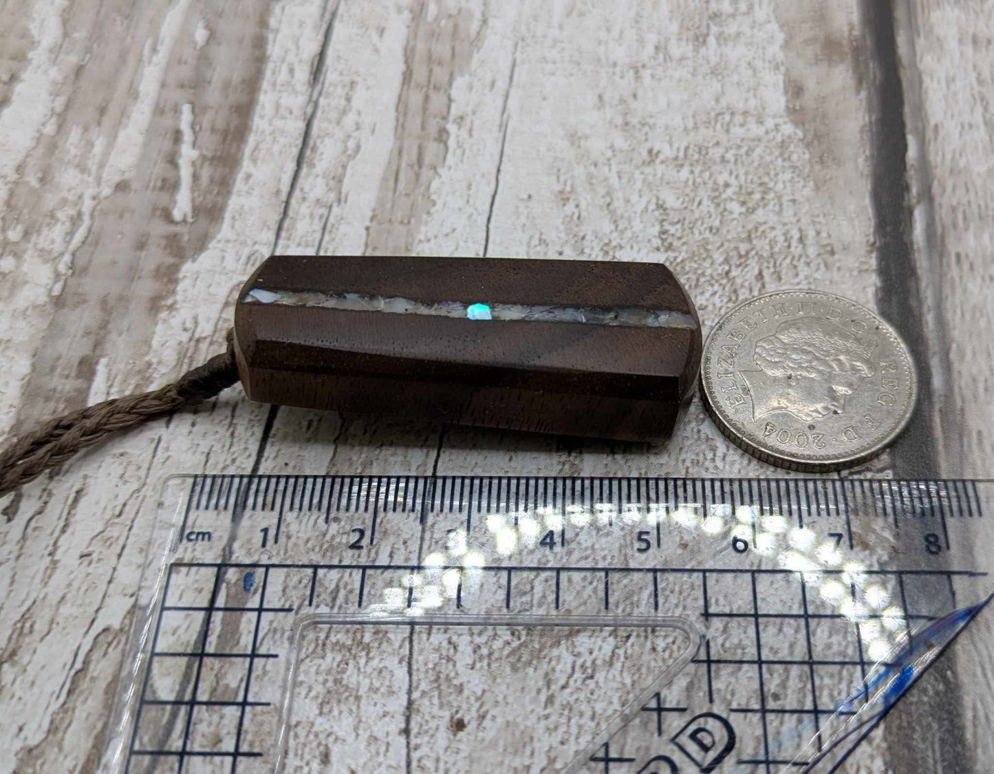 Walnut wood pendant with mussel shell inlay.