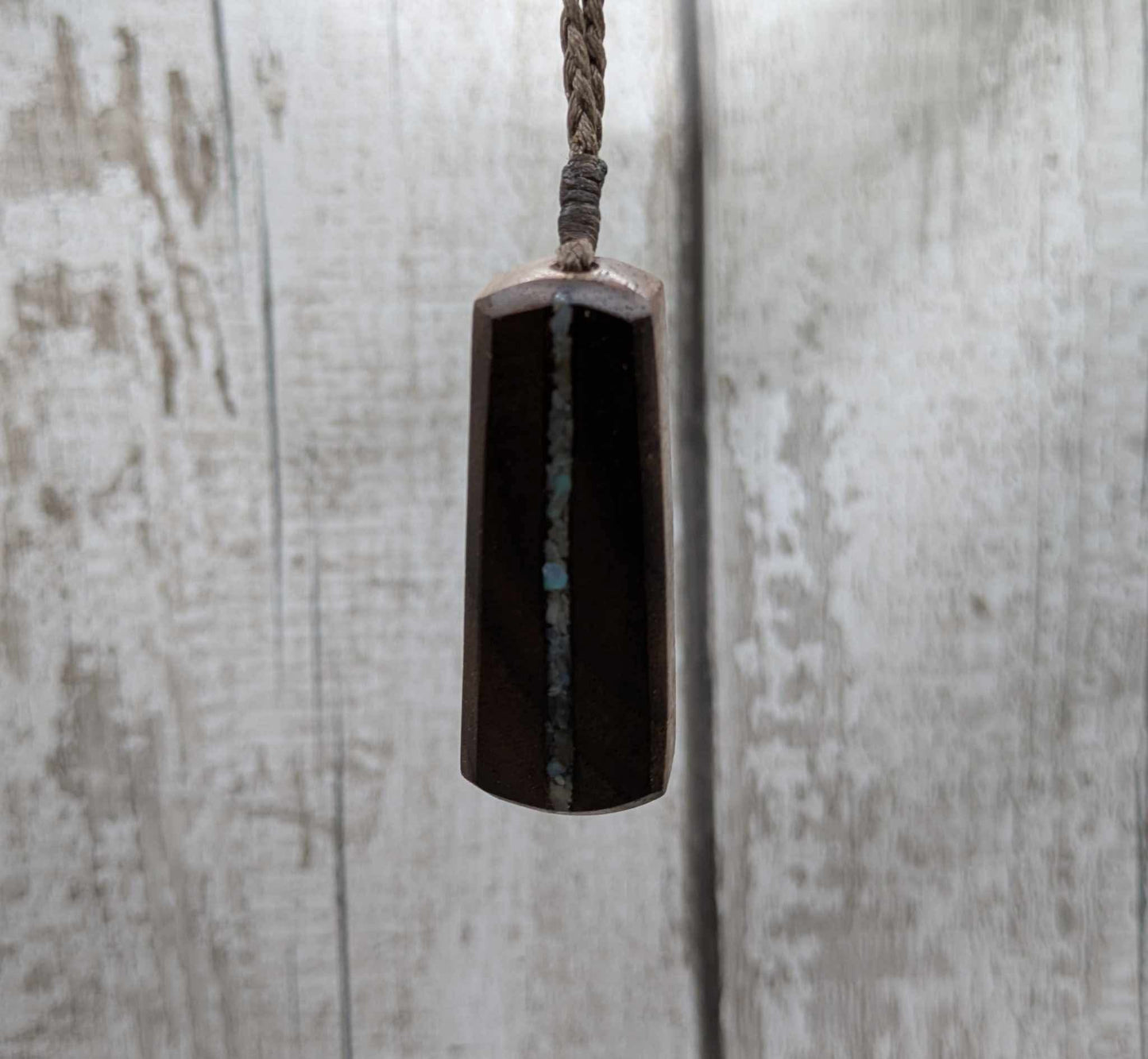 Walnut wood pendant with mussel shell inlay.