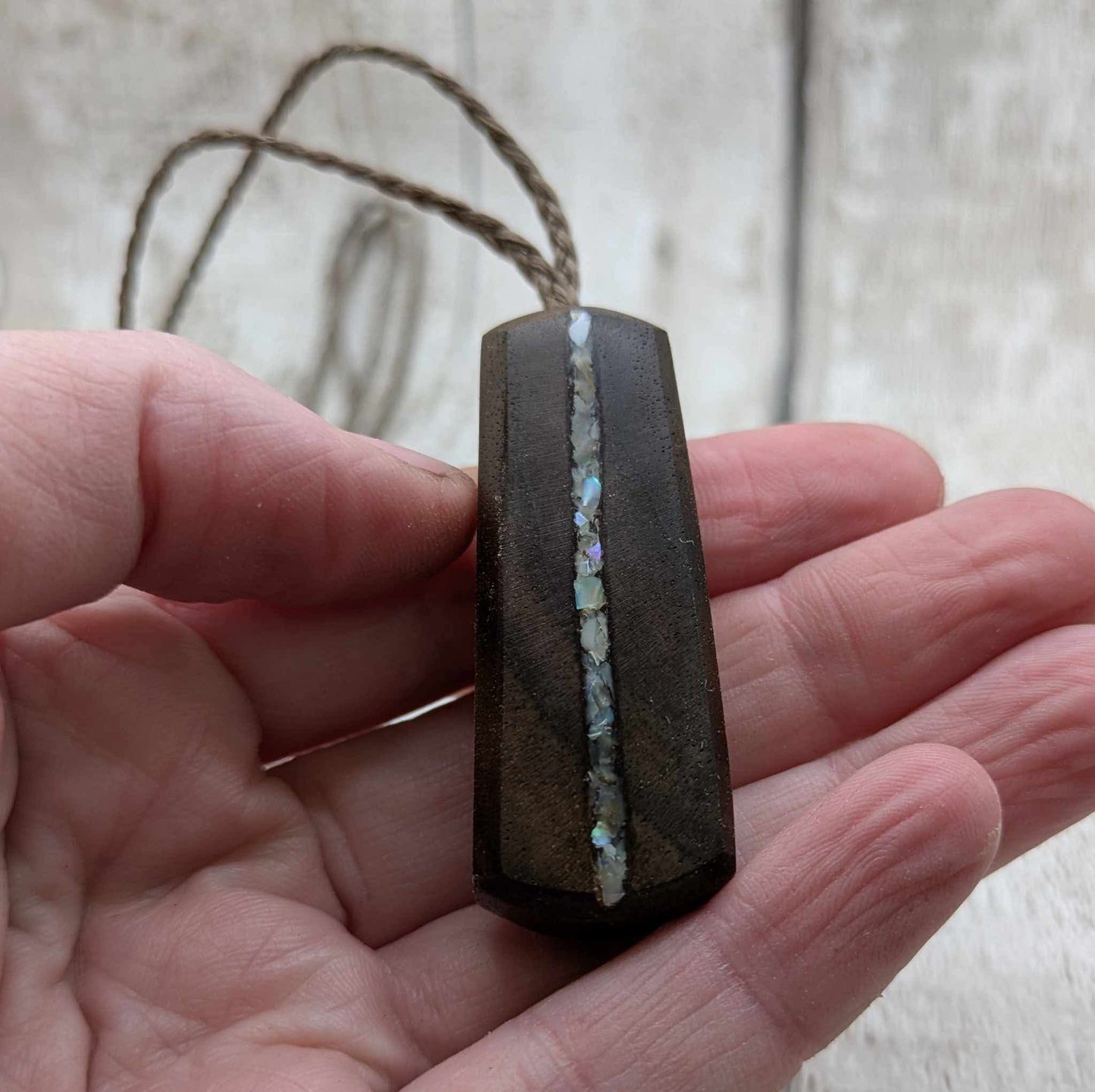 Walnut wood pendant with mussel shell inlay.