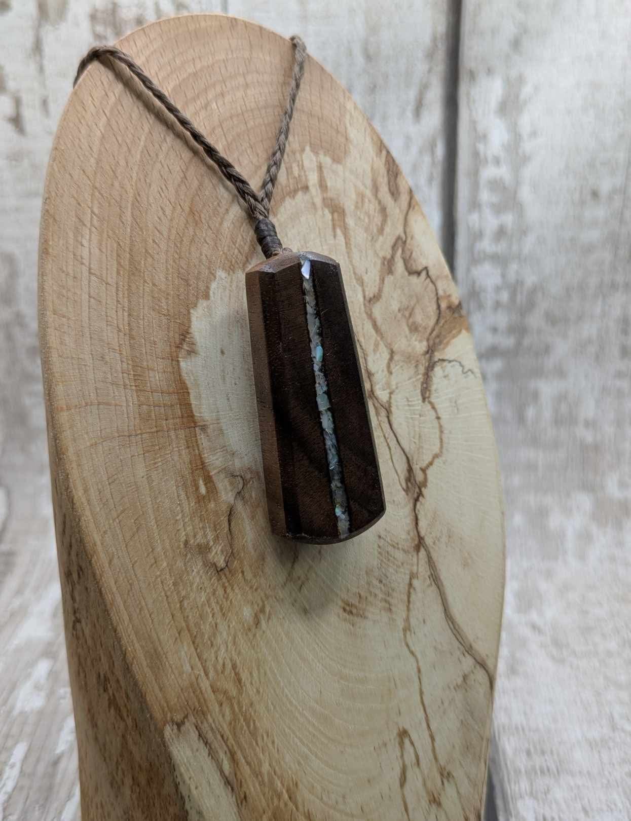 Walnut wood pendant with mussel shell inlay.