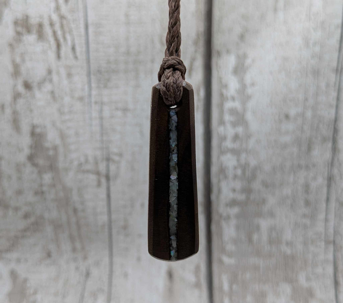 Walnut wood pendant with mussel shell inlay.