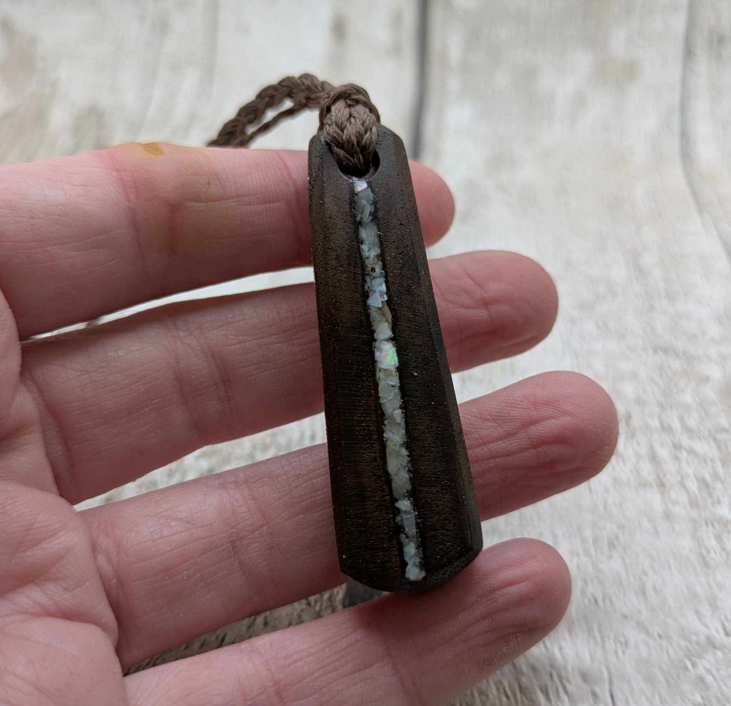 Walnut wood pendant with mussel shell inlay.