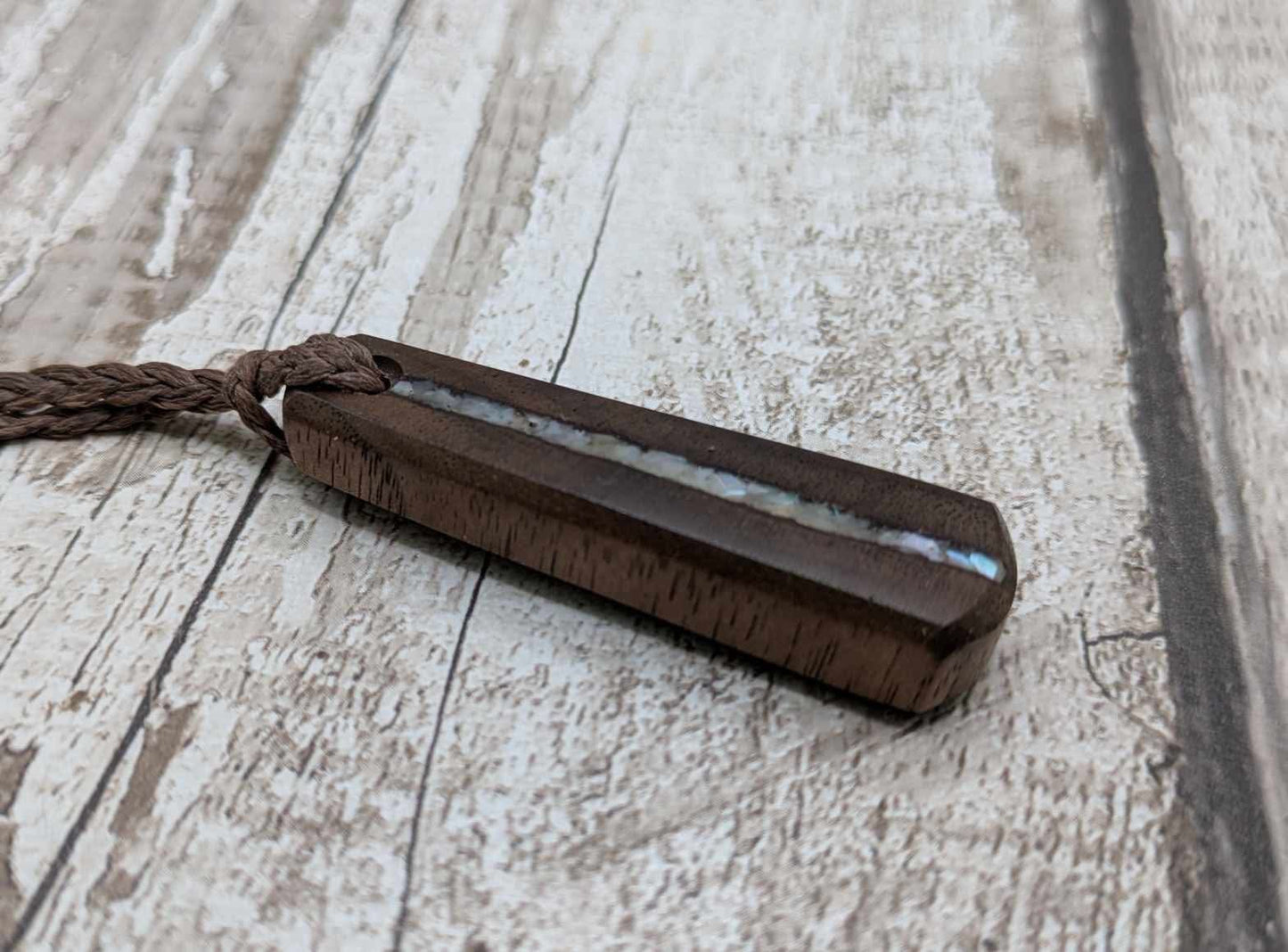 Walnut wood pendant with mussel shell inlay.