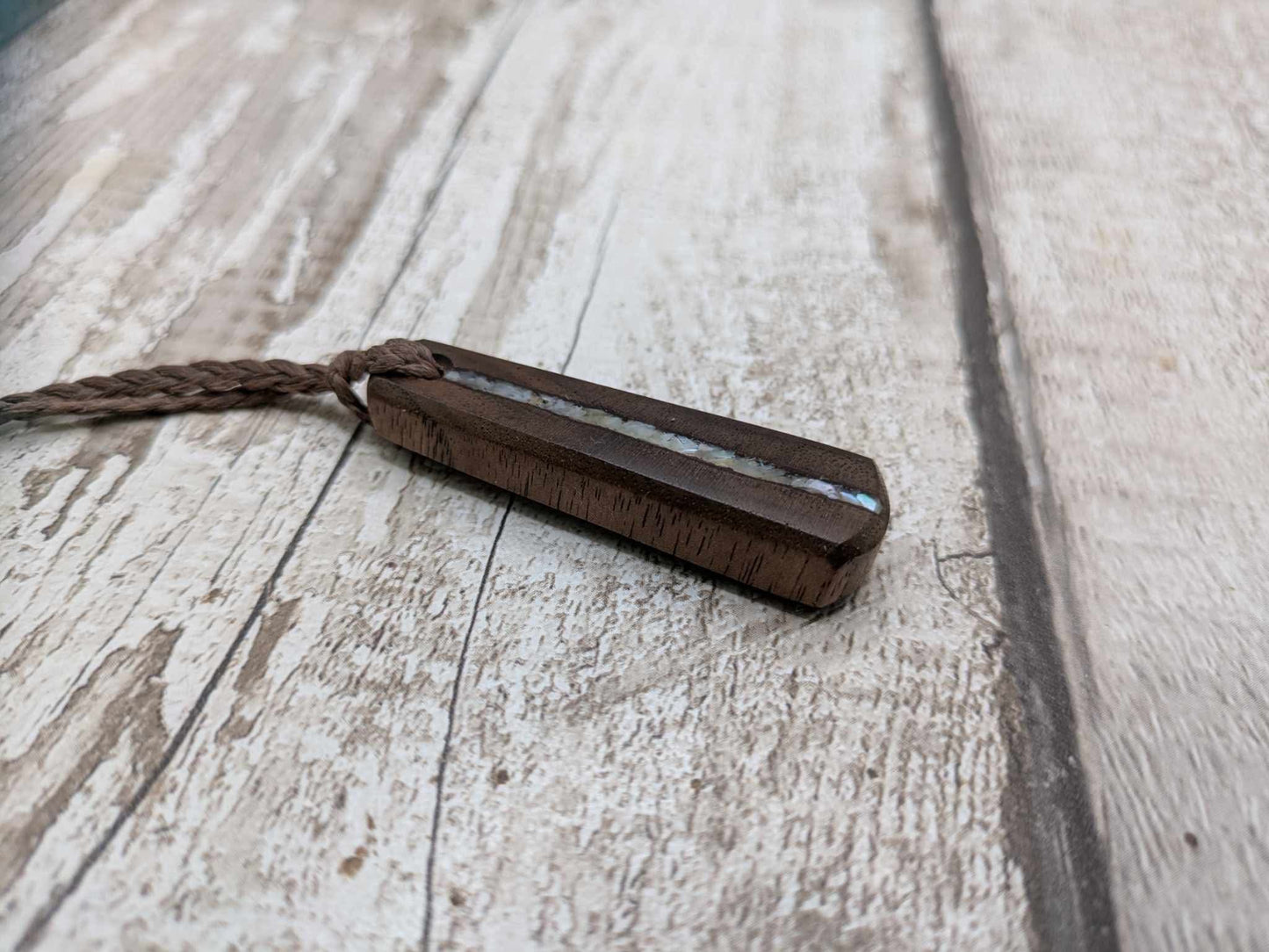 Walnut wood pendant with mussel shell inlay.