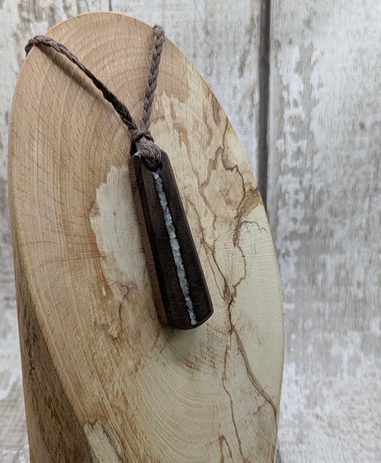 Walnut wood pendant with mussel shell inlay.