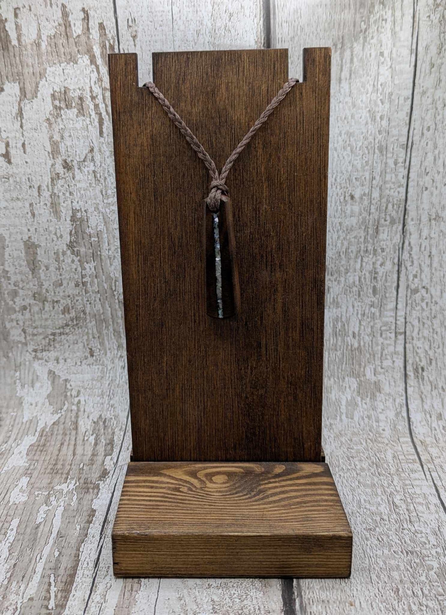 Walnut wood pendant with mussel shell inlay.