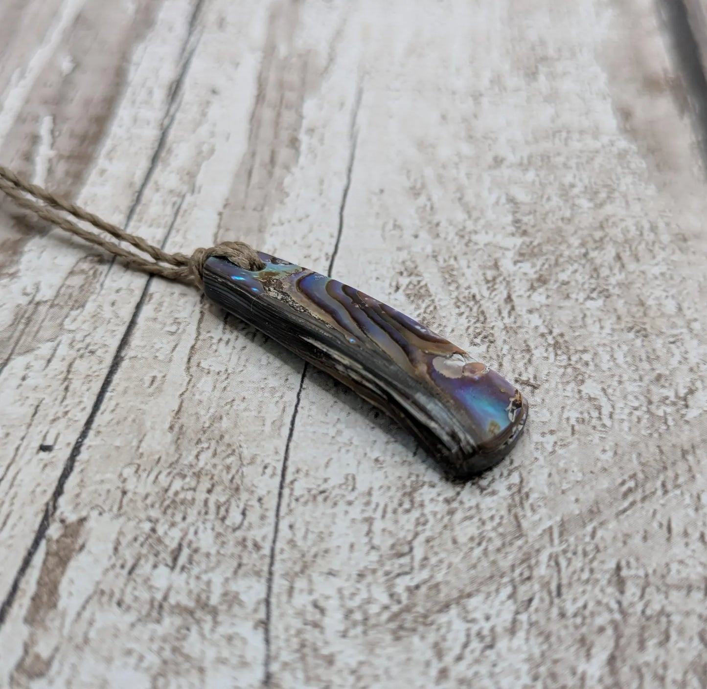 New Zealand rainbow pāua shell pendant on a churn chain.