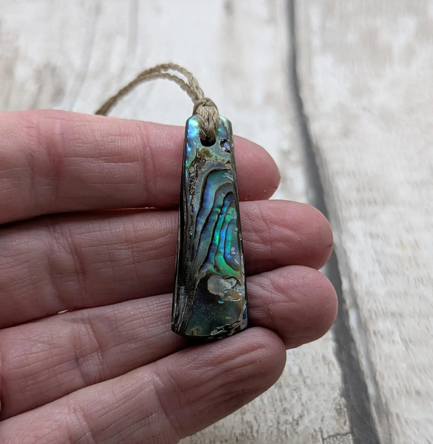 New Zealand rainbow pāua shell pendant on a churn chain.