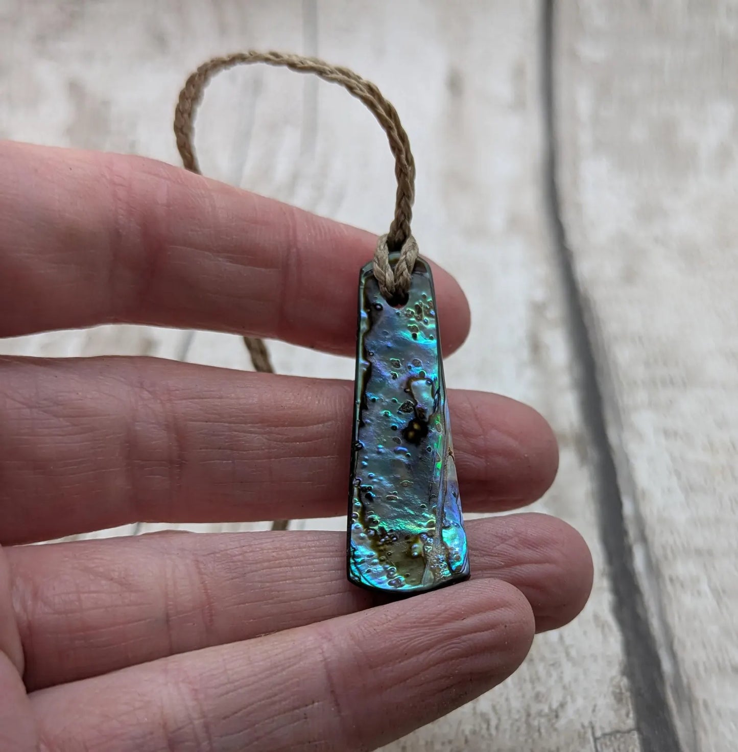 New Zealand rainbow pāua shell pendant on a churn chain.