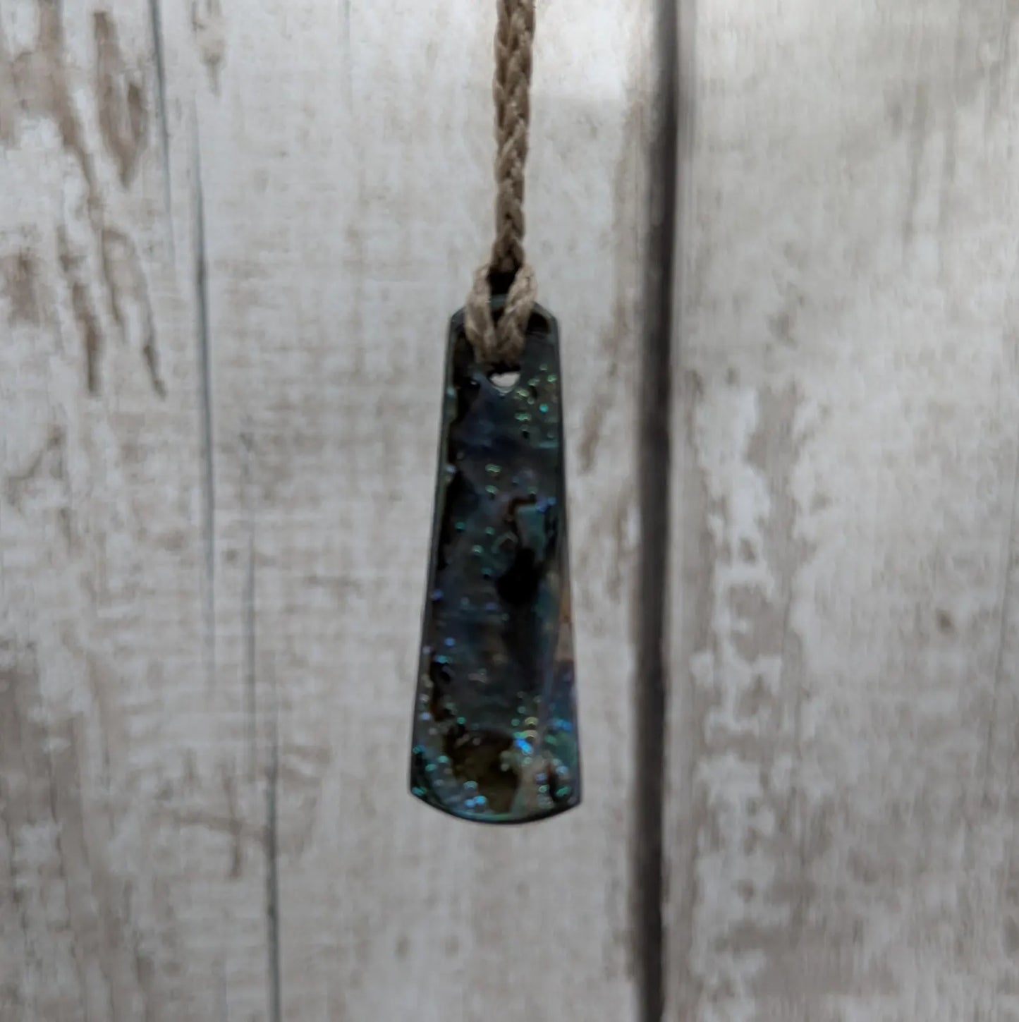 New Zealand rainbow pāua shell pendant on a churn chain.