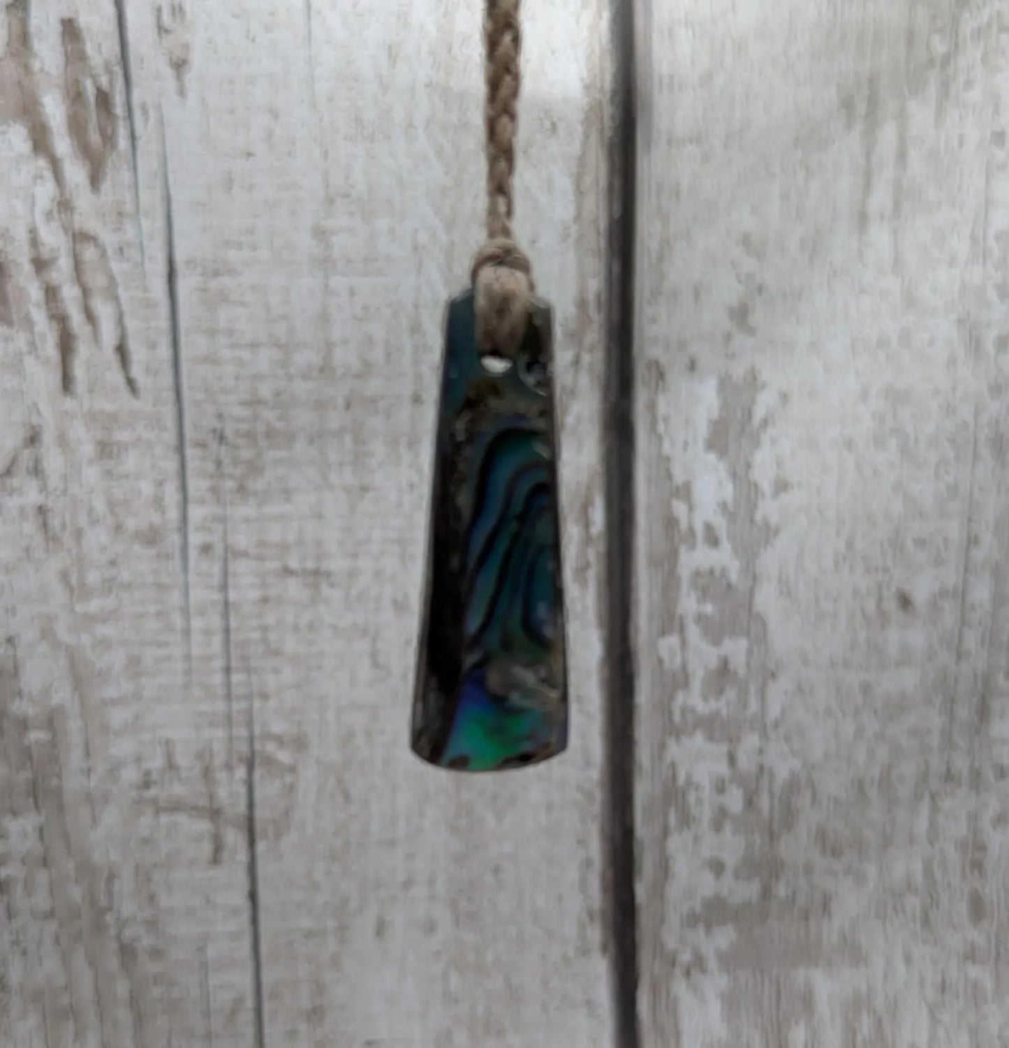 New Zealand rainbow pāua shell pendant on a churn chain.