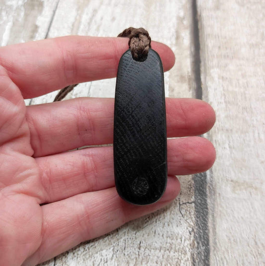 Bog oak hand carved pendant with a moldavite dot inlay.