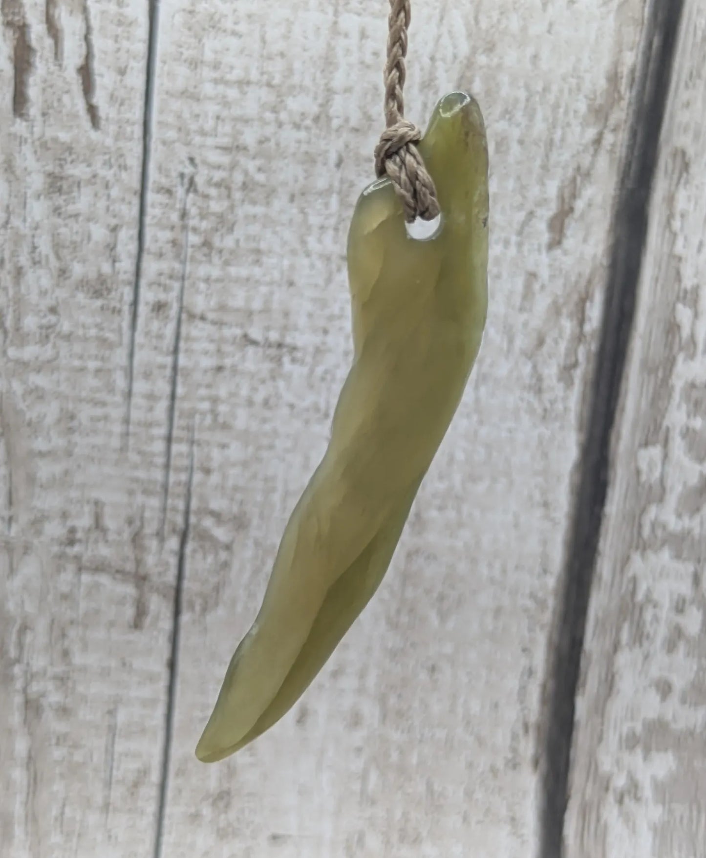 Tumbled nephrite jade Pounamu stone pendant.