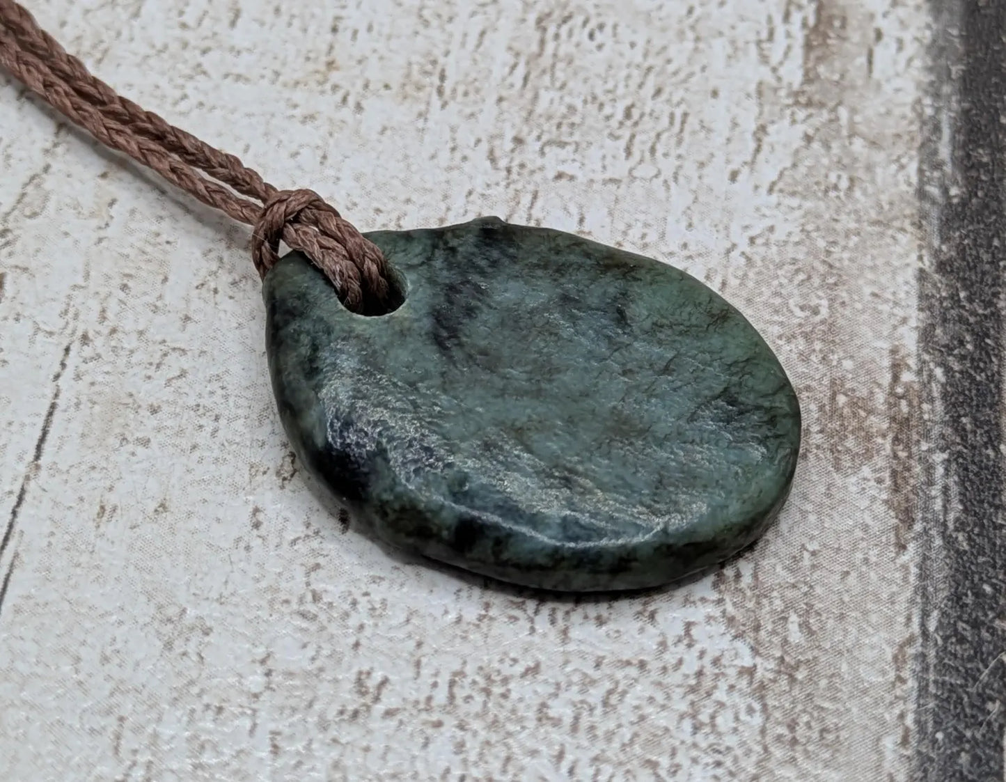 Tumble polished New Zealand Pounamu greenstone pendant.