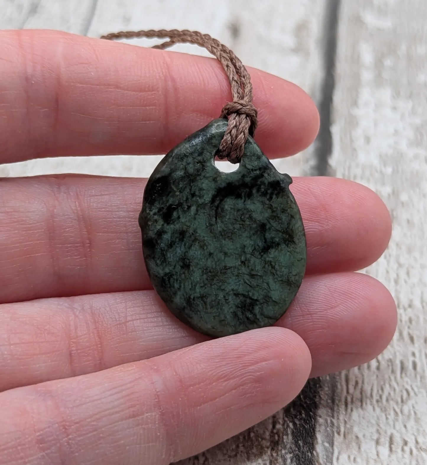 Tumble polished New Zealand Pounamu greenstone pendant.