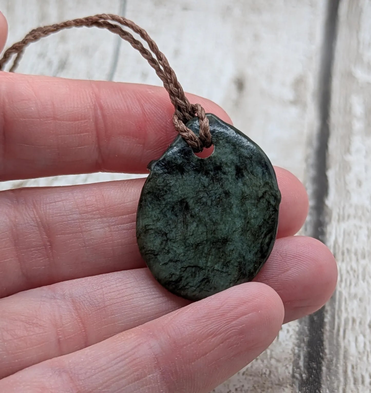 Tumble polished New Zealand Pounamu greenstone pendant.