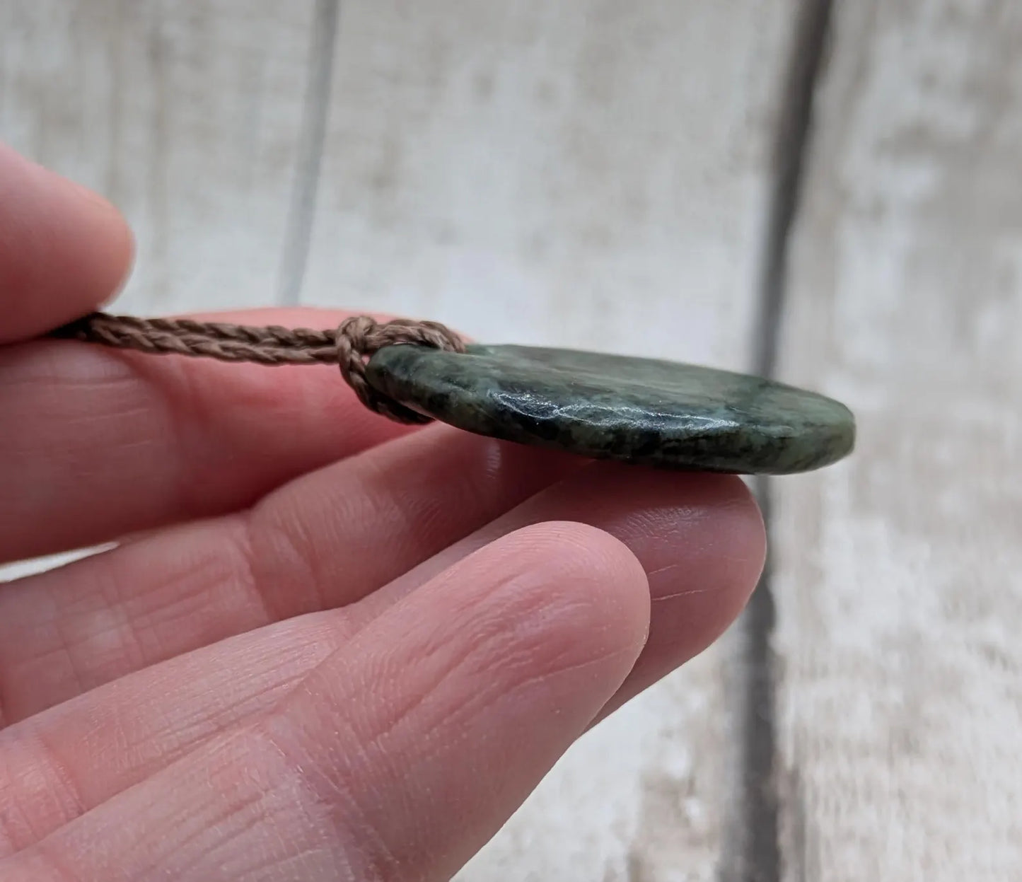 Tumble polished New Zealand Pounamu greenstone pendant.