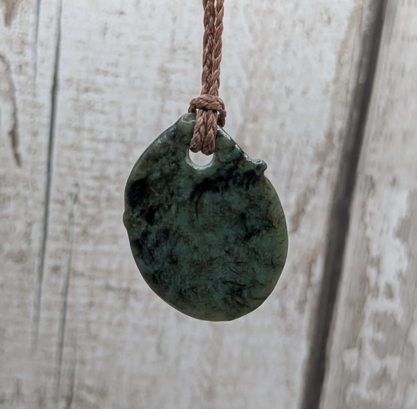 Tumble polished New Zealand Pounamu greenstone pendant.