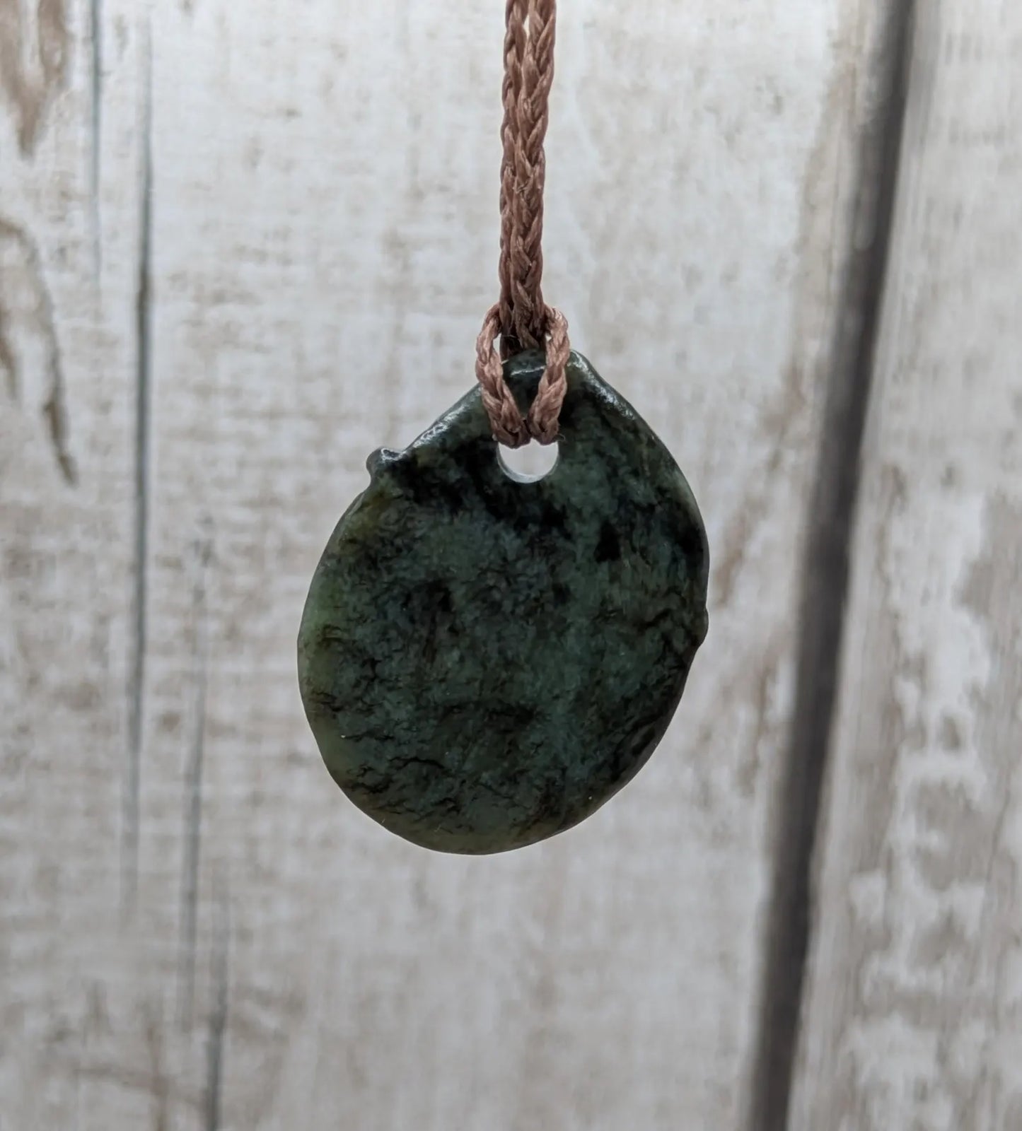 Tumble polished New Zealand Pounamu greenstone pendant.