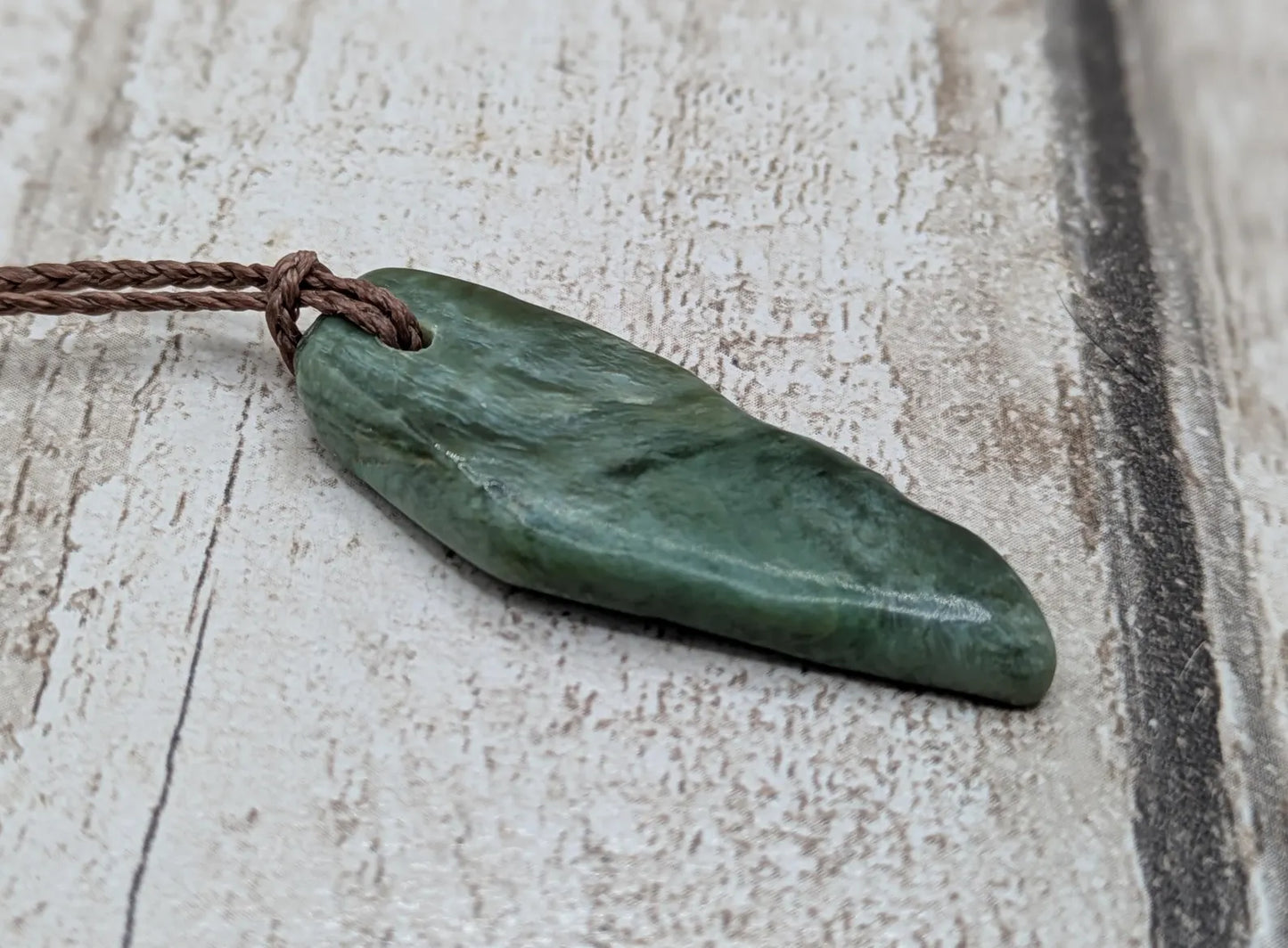 Chatoyant New Zealand tumbled Pounamu greenstone pendant.