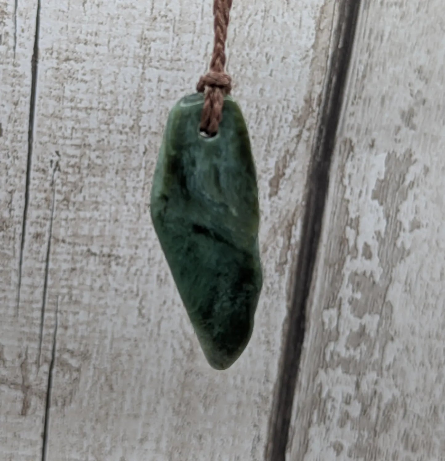 Chatoyant New Zealand tumbled Pounamu greenstone pendant.