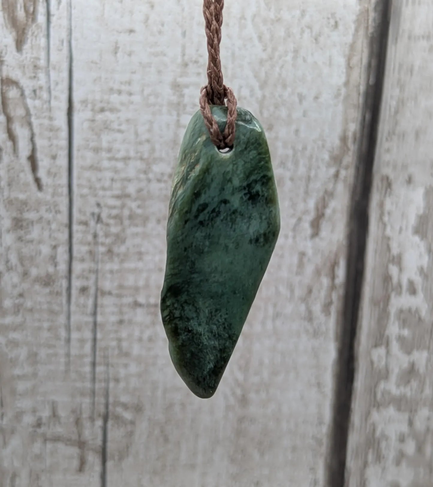 Chatoyant New Zealand tumbled Pounamu greenstone pendant.