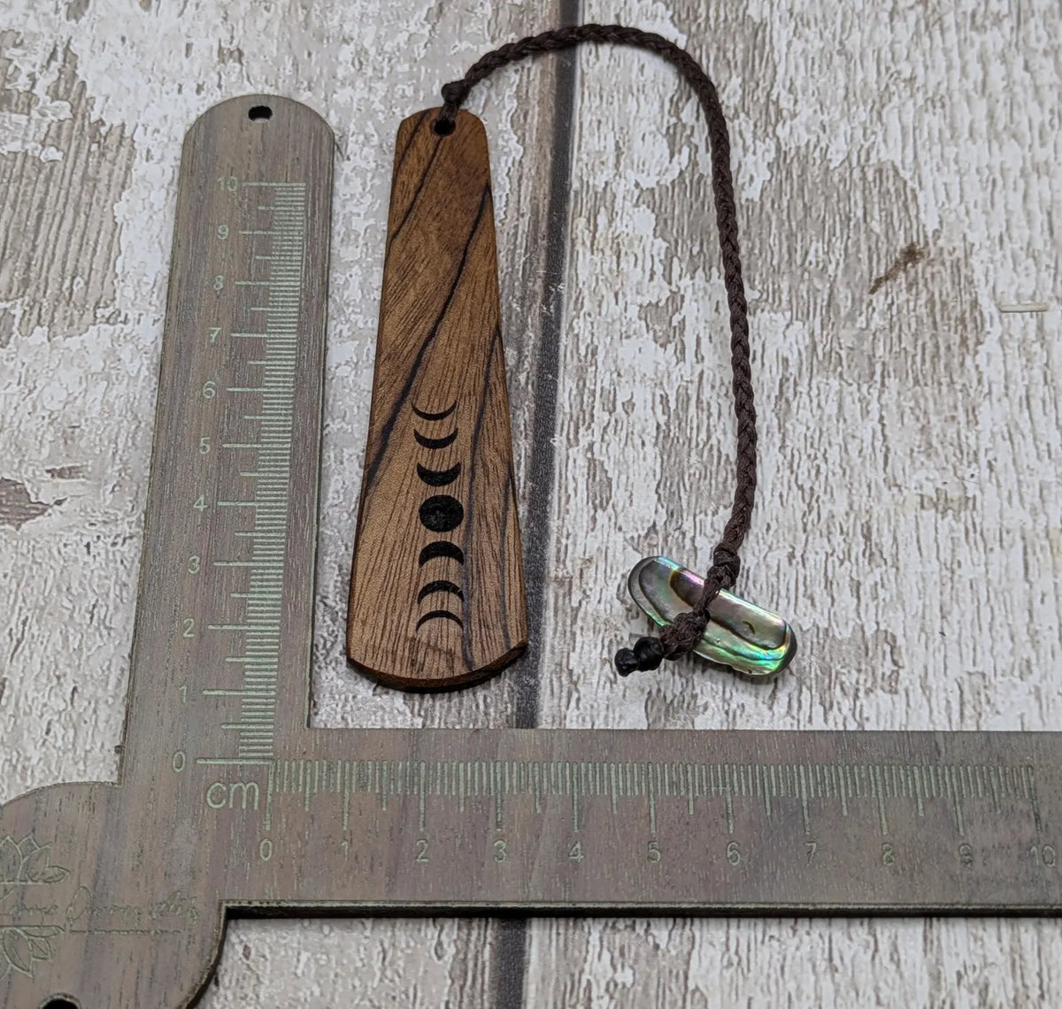Walnut wood moon phrase laser printed bookmark with pāua abalone shell bead tassel.