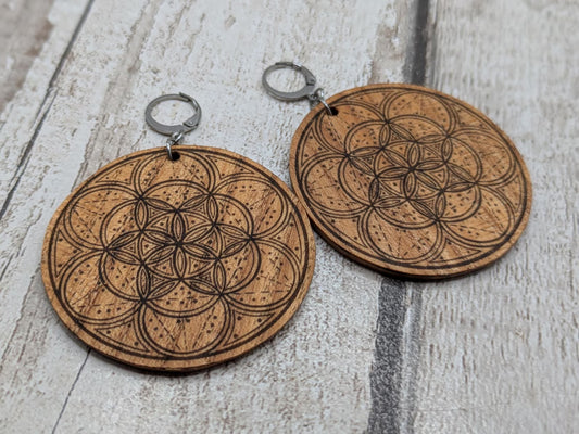 Oak wood disk earrings with laser printed geometric flower of life design, on stainless steel findings.