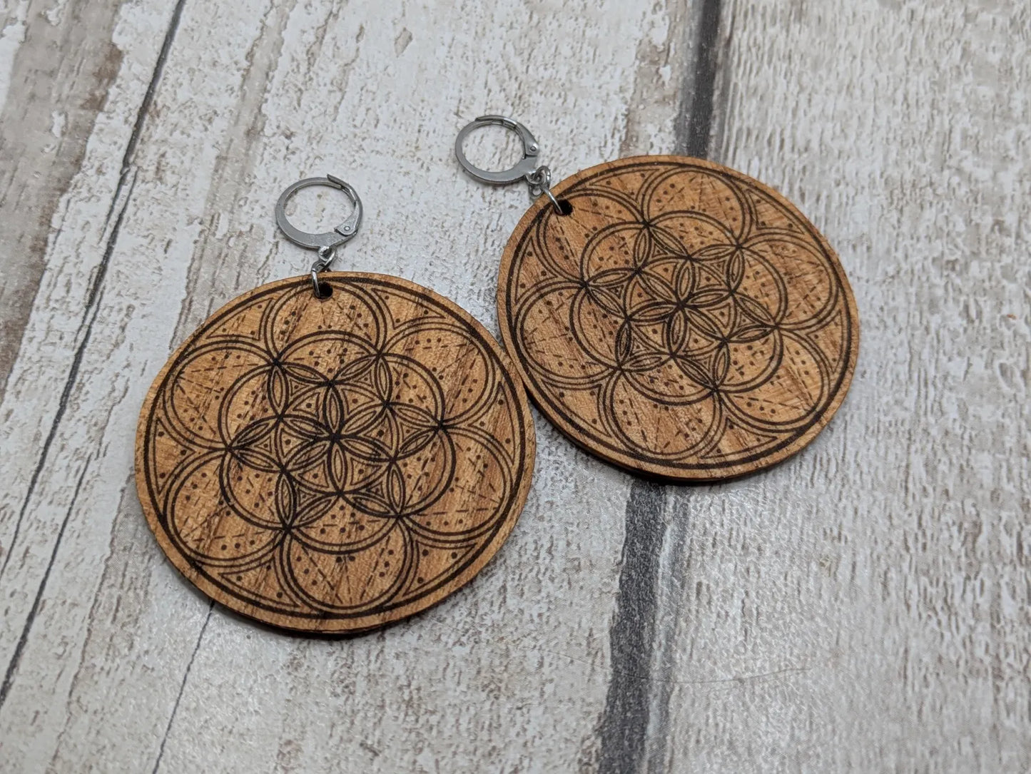 Oak wood disk earrings with laser printed geometric flower of life design, on stainless steel findings.