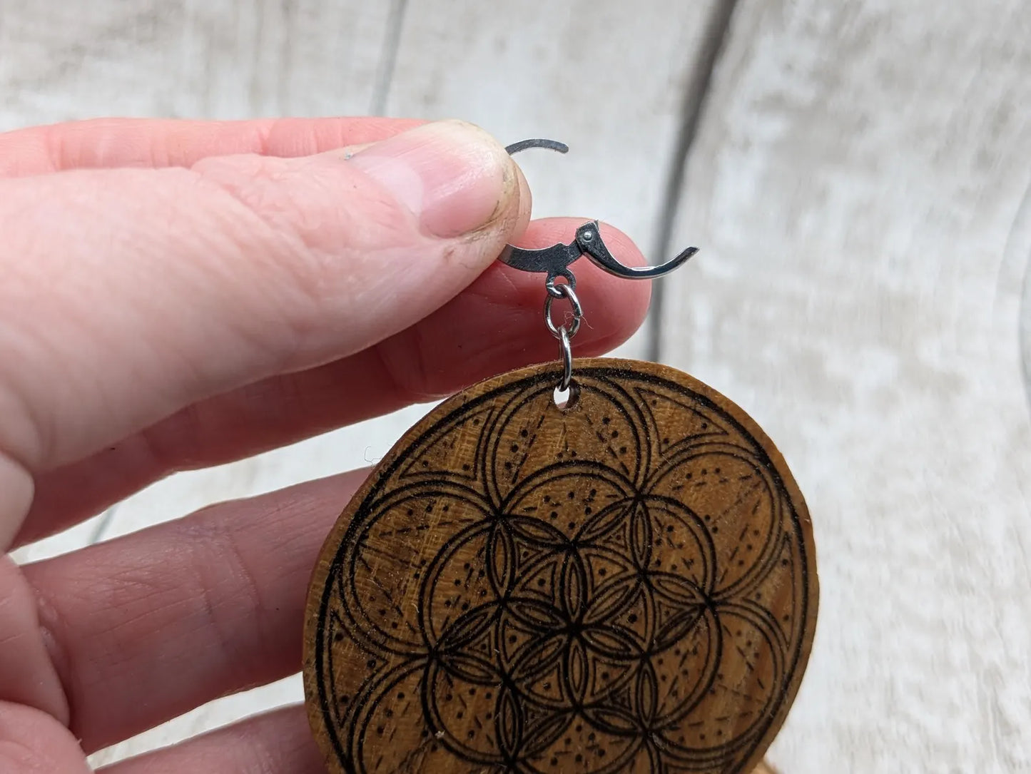 Oak wood disk earrings with laser printed geometric flower of life design, on stainless steel findings.