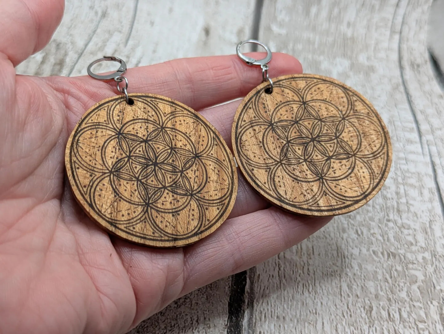 Oak wood disk earrings with laser printed geometric flower of life design, on stainless steel findings.