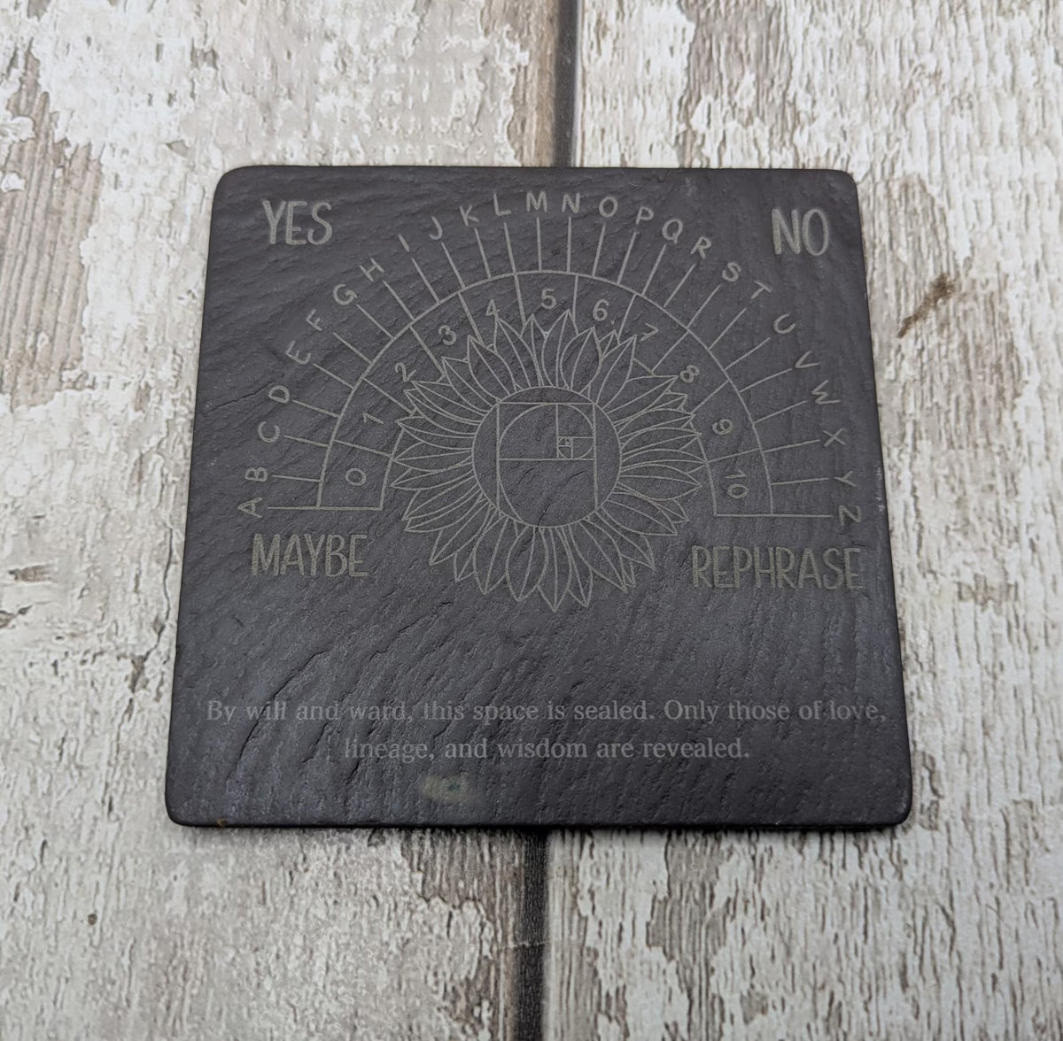 Welsh slate pendulum dowsing board with sunflower design.