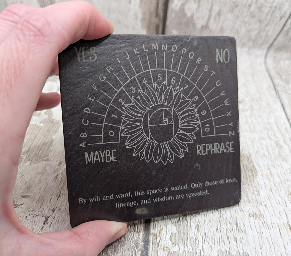 Welsh slate pendulum dowsing board with sunflower design.