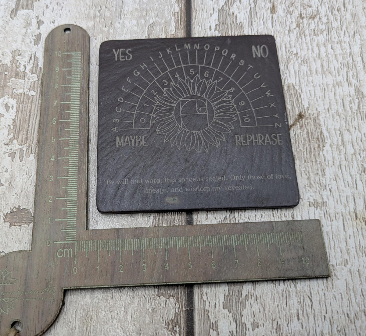 Welsh slate pendulum dowsing board with sunflower design.