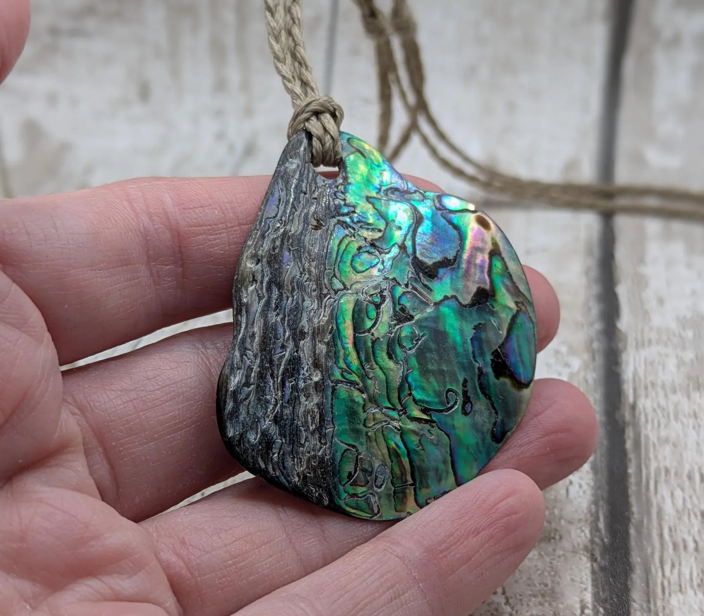 Free form naturally tumbled New Zealand rainbow Pāua pendant.