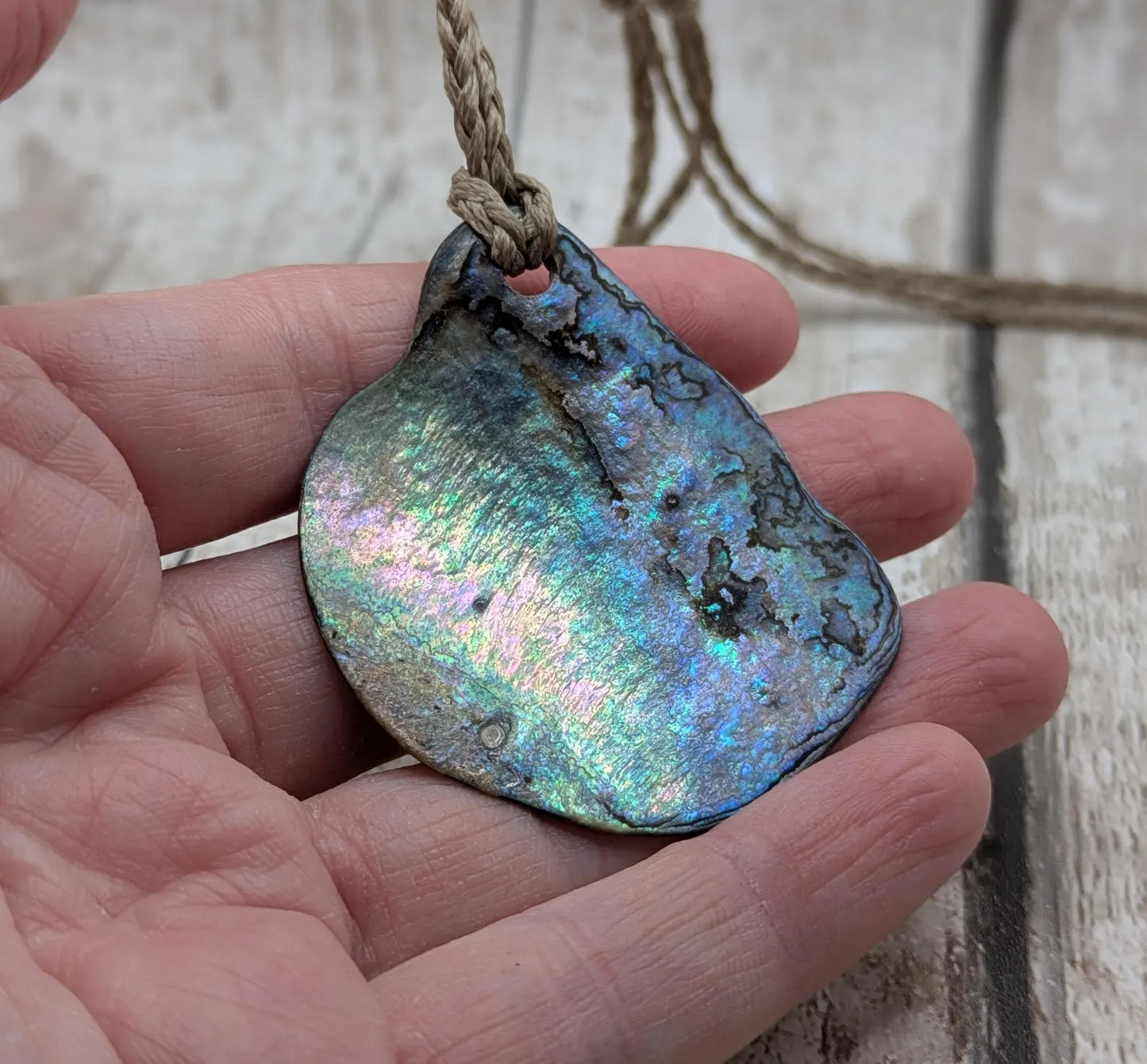 Free form naturally tumbled New Zealand rainbow Pāua pendant.