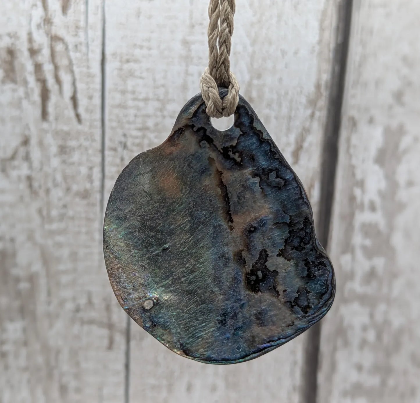Free form naturally tumbled New Zealand rainbow Pāua pendant.