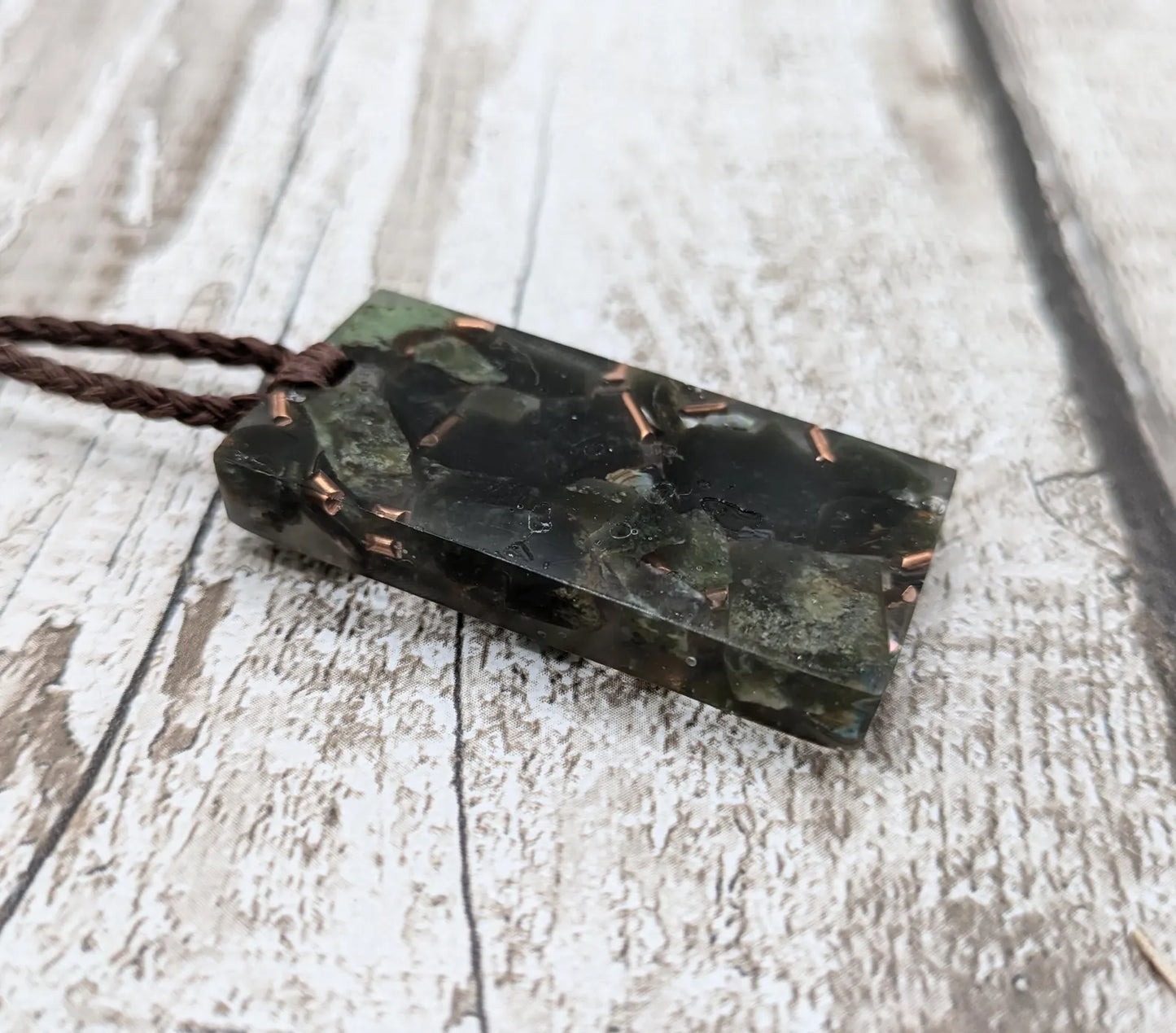 Mixed nephrite jade and copper in resin pendant.