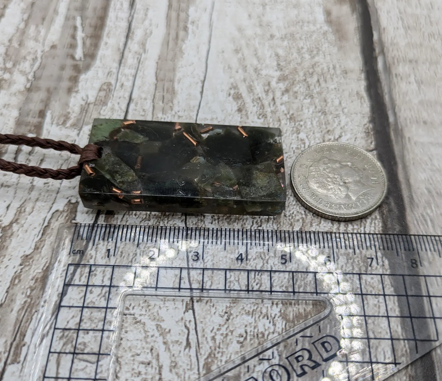 Mixed nephrite jade and copper in resin pendant.