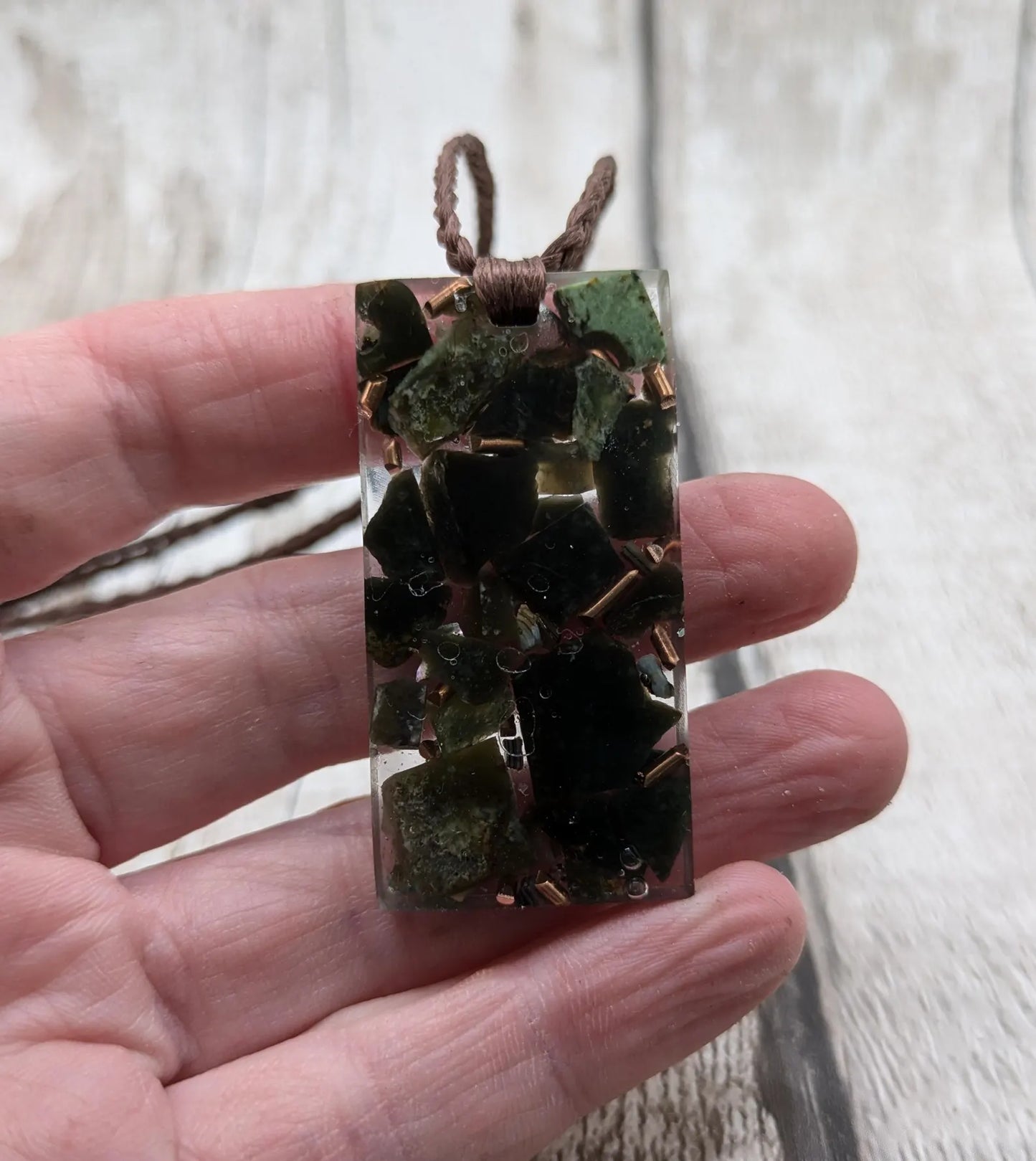 Mixed nephrite jade and copper in resin pendant.