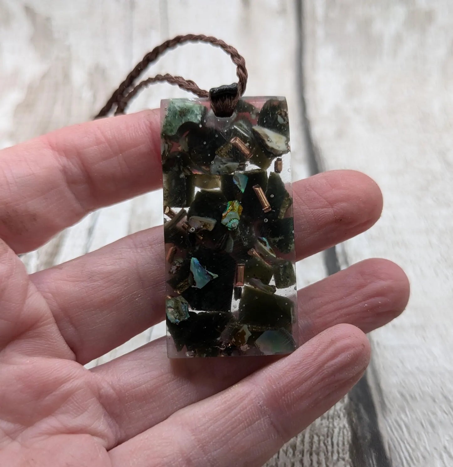 Mixed nephrite jade and copper in resin pendant.