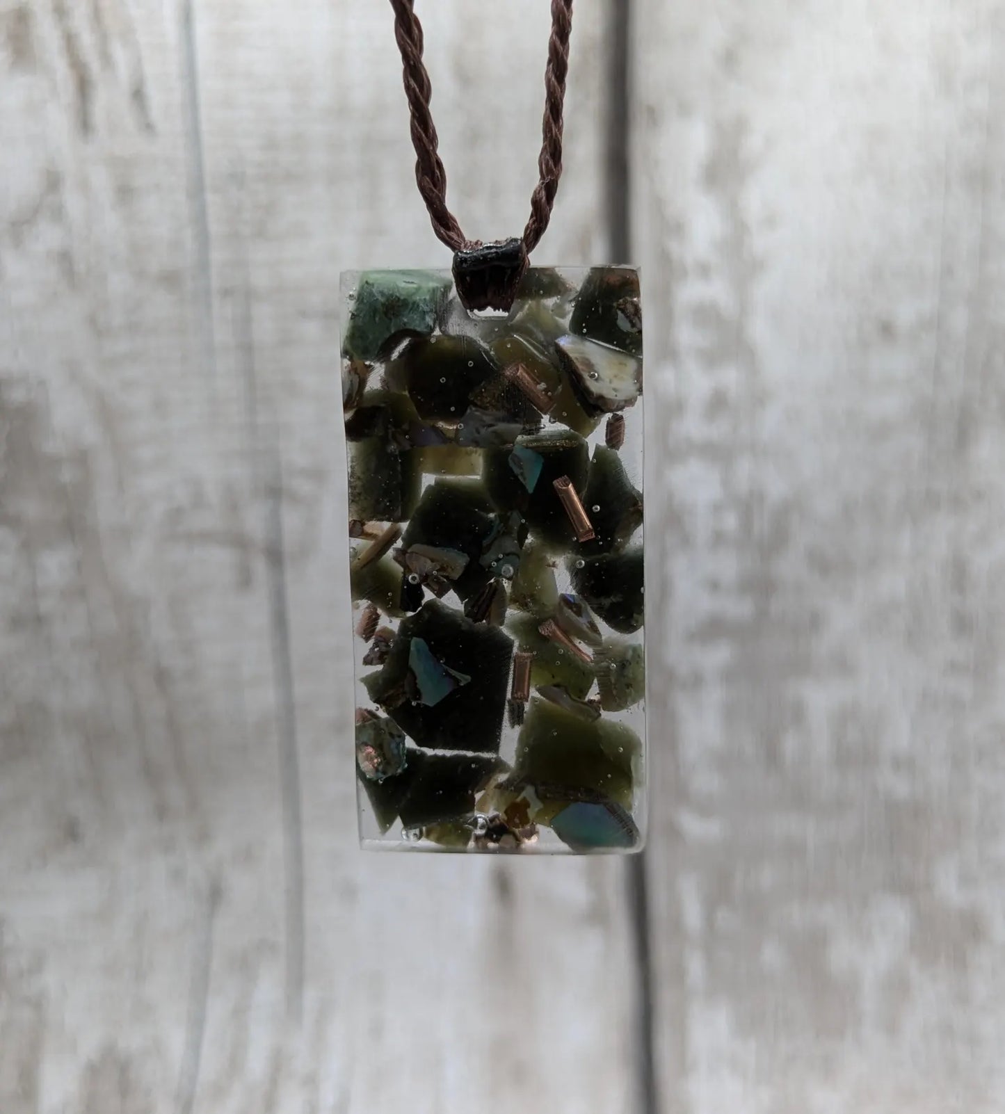 Mixed nephrite jade and copper in resin pendant.