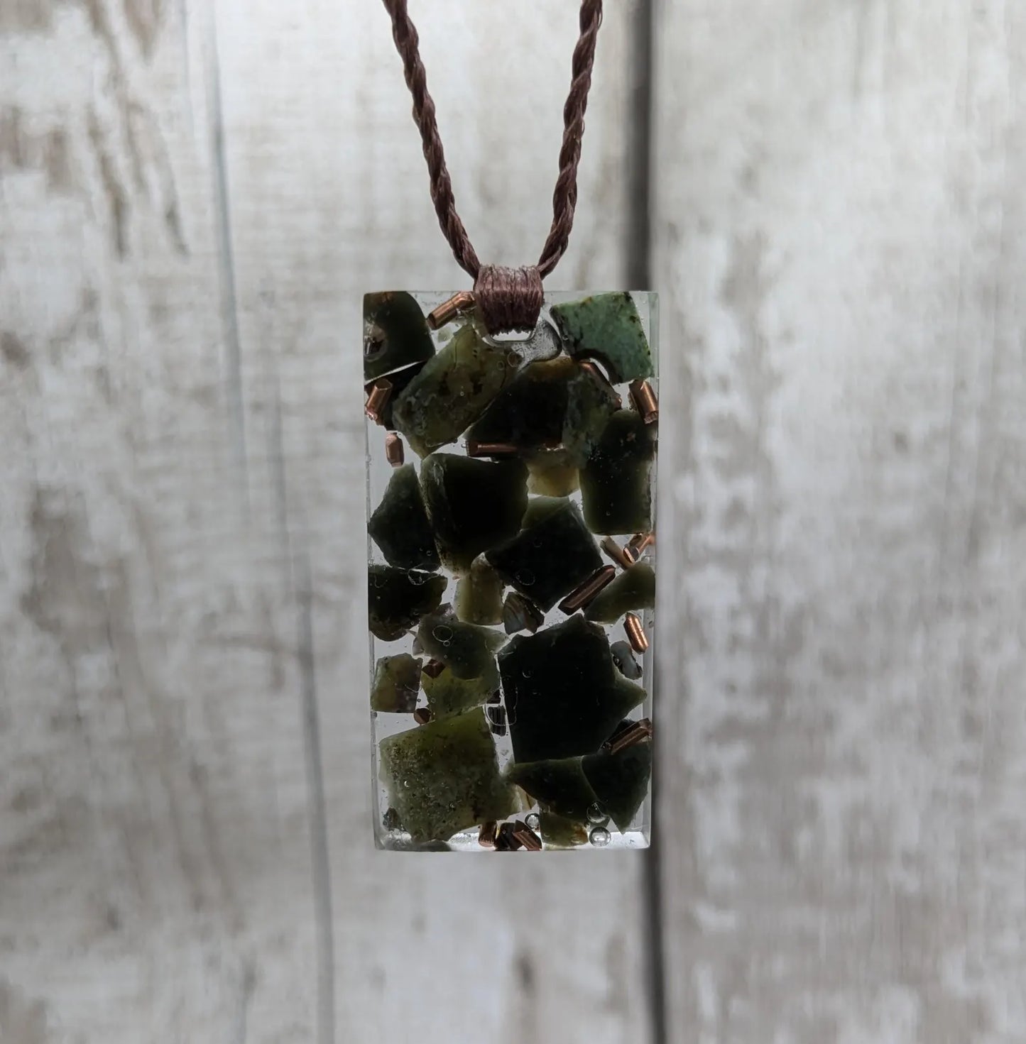 Mixed nephrite jade and copper in resin pendant.