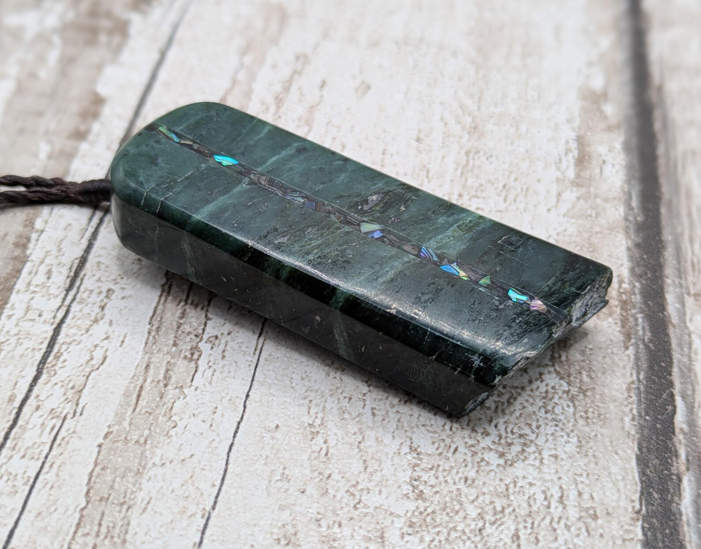 new Zealand pounamu serpentine with rainbownpāua inlay and raw edge.