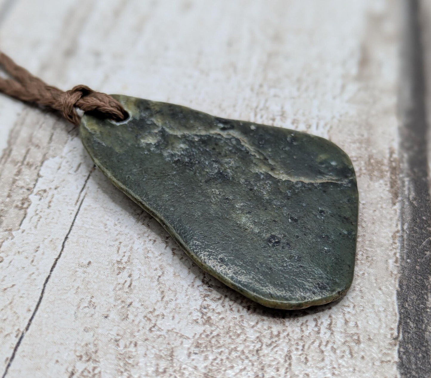 Tumbled polished New Zealand Pounamu greenstone pebble pendant.