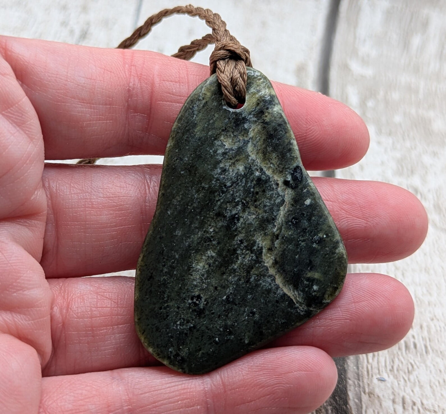 Tumbled polished New Zealand Pounamu greenstone pebble pendant.